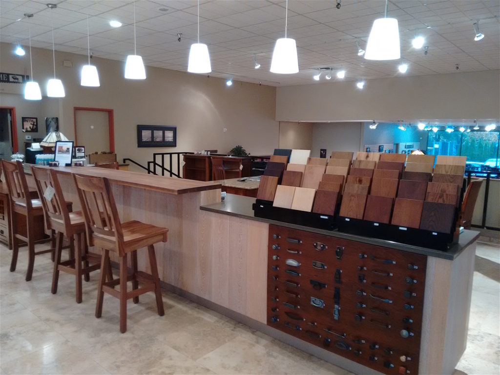 Handcrafted solid wood furniture showroom with stain and hardware samples at the counter.
