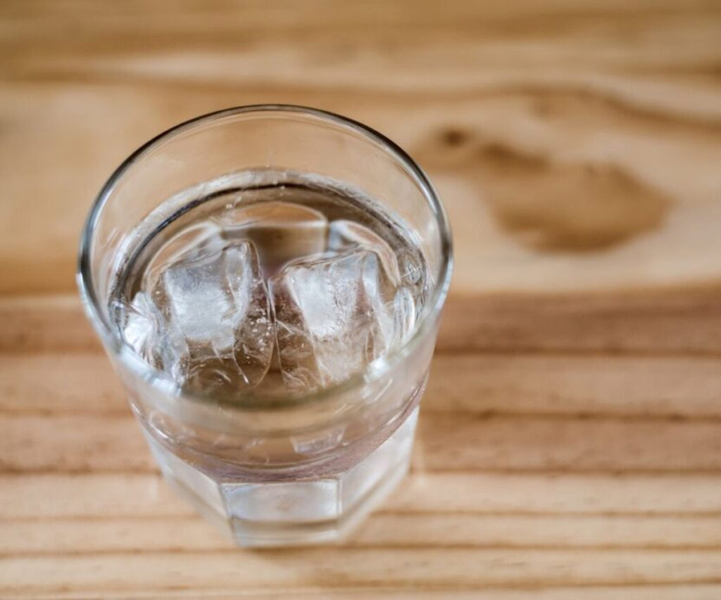 Glass of ice water on wood table leaving a watermark